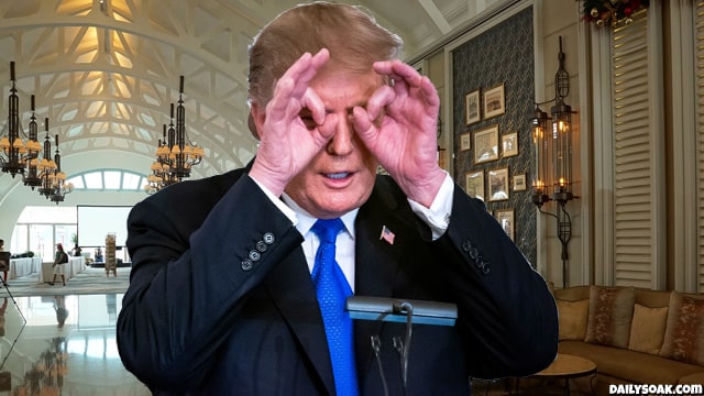 Donald Trump with his hands circled around his eyes while standing inside Mar-A-Lago.