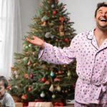 Man laughing while his young son cries in front of Christmas tree.