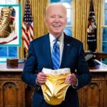 Joe Biden holding up a golden diaper nest to Donald Trump's sneakers.