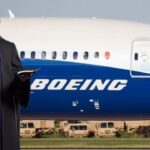 Priest in black robes standing in front of a Boeing plane.
