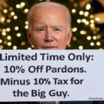 President Joe Biden holding up a sign standing in front of a Christmas tree.