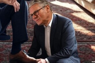 UK Prime Minister Keir Starmer polishing a EU leader's shoes.