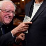 Bernie Sanders taking money out of someone's pocket inside of a restaurant.