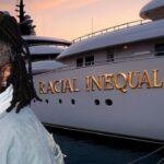 Whoopi Goldberg standing in front of a yacht called "Racial Inequality."