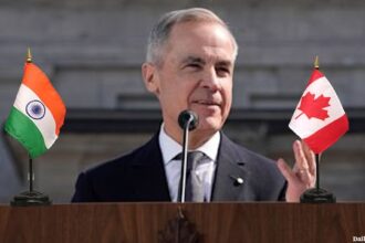 Mark Carney giving a speech on stage with a Canada flag and India flag.