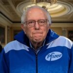 Bernie Sanders wearing a blue and white Pfizer jacket inside of Congress for RFK Jr. hearing.