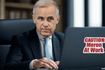 Canada Prime Minister Mark Carney sitting at desk looking at laptop.