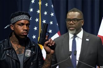 Black Chicago Mayor Brandon Johnson on stage next to a male, black gang member.
