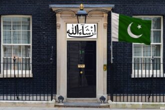 UK Prime Minister's office on 10 Downing Street with a green Pakistan flag in front.