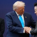Mark Carney standing in a corner watching President Donald Trump during APEC summit in South Korea.