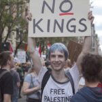 Blue-haired, skinny white man holding up a "No Kings" sign.