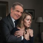 Andrew Cuomo wearing a suit and groping a young blonde woman from behind.