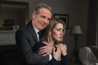 Andrew Cuomo wearing a suit and groping a young blonde woman from behind.