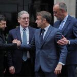 European leaders UK Prime Minister Keir Starmer, Volodymyr Zelensky, Friedrich Merz, and Emmanuel Macron hugging on street in London.