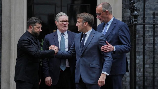 European leaders UK Prime Minister Keir Starmer, Volodymyr Zelensky, Friedrich Merz, and Emmanuel Macron hugging on street in London.