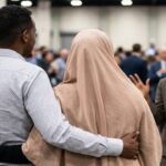 Ilhan Omar wearing Muslim hijab staring angrily at her brother holding another Somali woman.