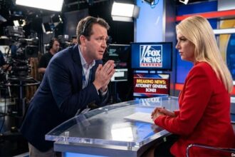 Fox News producer pleading with Pam Bondi dressed in red jacket sitting down in a studio.