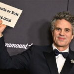 Celebrities Mark Ruffalo wearing a suit holding a sign with the words "Canada or Bust" at the Golden Globe awards.