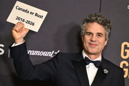 Celebrities Mark Ruffalo wearing a suit holding a sign with the words "Canada or Bust" at the Golden Globe awards.