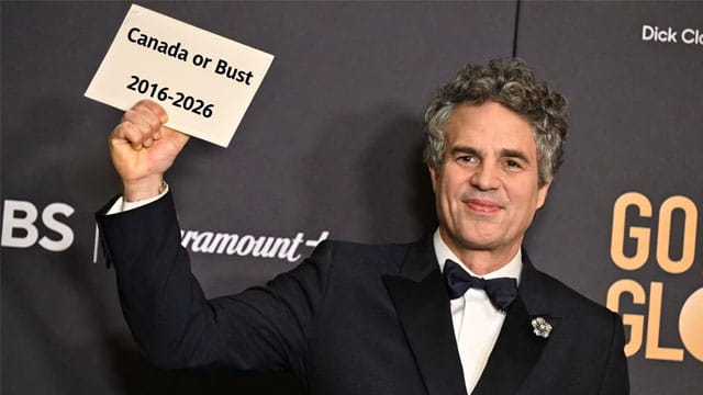 Celebrities Mark Ruffalo wearing a suit holding a sign with the words "Canada or Bust" at the Golden Globe awards.
