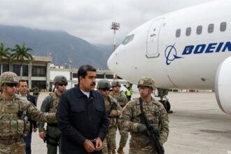 Venezuela dictator Nicolás Maduro in handcuffs surrounded by US military standing in front of a Boeing plane.