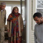 Somali mom and dad standing at doorway of house yelling at their Somali son with his head down outside in snowy Minnesota.