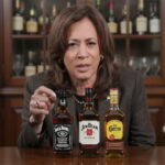 Kamala Harris speaking at a table lined with alcoholic bottles.