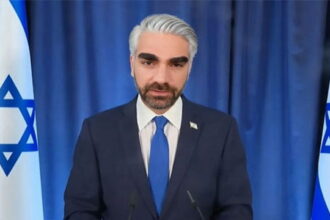 Jewish podcaster Ben Shapiro wearing a suit and a white wig posing as Israel Prime Minister Benjamin Netanyahu.