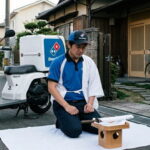 Japanese Dominos delivery driver committing seppuku in front of a Japan house.