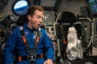 NASA Artemis II astronaut sitting in seat inside space rocket.