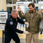 Male TSA agent checking the pockets of another man at a Walmart store.
