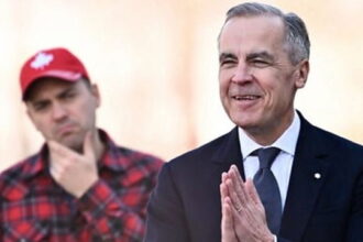Canada Prime Minister Mark Carney wearing a suit and standing in front of a Canadian man wearing a flannel shirt.