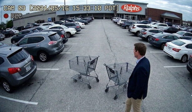 Video of Democrat Eric Swalwell wearing suit pushing shopping cart in parking lot.