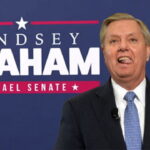 Lindsey Graham wearing a suit standing in front of a campaign sign with the words "Israel Senate."