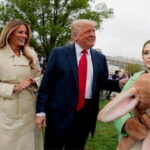 Pam Bondi wearing an Easter Bunny costume standing next to President Donald Trump and wife Melania on White House lawn.
