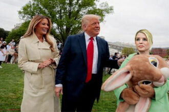 Pam Bondi wearing an Easter Bunny costume standing next to President Donald Trump and wife Melania on White House lawn.