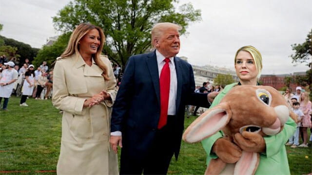 Pam Bondi wearing an Easter Bunny costume standing next to President Donald Trump and wife Melania on White House lawn.