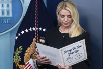 Blonde female Pam Bondi reading a letter on stage at the White House press room.