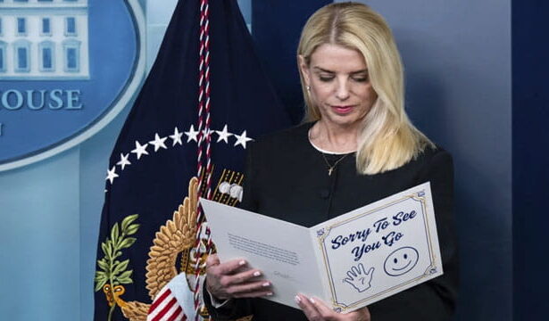 Blonde female Pam Bondi reading a letter on stage at the White House press room.