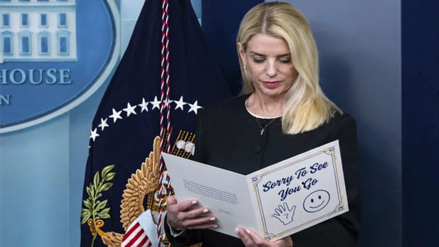 Blonde female Pam Bondi reading a letter on stage at the White House press room.