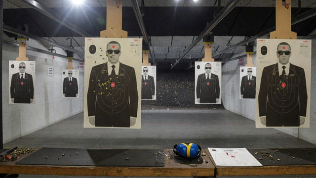 Gun range with target silhouettes of men wearing black suits and sunglasses resembling Secret Service agents.