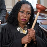 Black female US Supreme Court Justice Ketanji Brown Jackson holding a plumber's plunger.