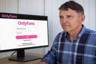 Ed Gallrein sitting at a desk looking at a computer screen on the OnlyFans website.