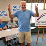 Joe Biden wearing shirt and shorts inside a senior home celebrating with other old people.