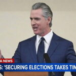 California Governor Gavin Newsom speaking behind a podium on the recent Los Angeles and governor's primary elections.