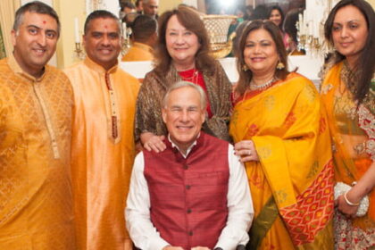 Texas Governor Greg Abbott wearing traditional Indian clothing sitting beside various male and female Indian H1B workers.