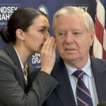 A female aide whispering into South Carolina Senator Lindsey Graham's ear on stage.