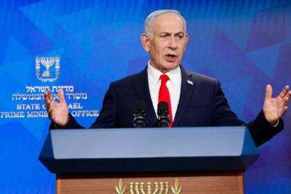 Israel Prime Minister Benjamin Netanyahu wearing a suit on stage speaking.