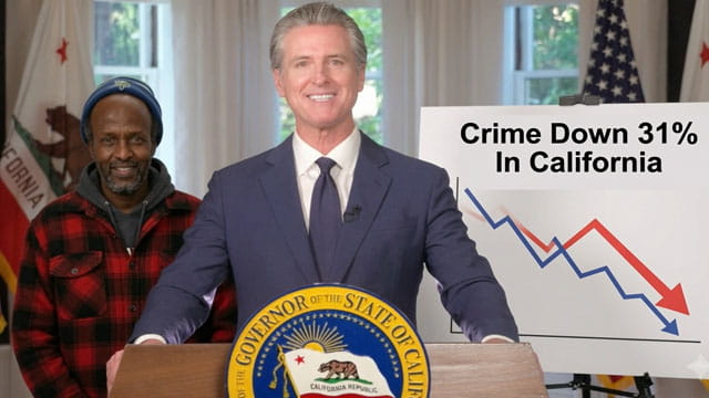 California Governor Gavin Newsom wearing a suit standing behind a podium and a male black Somali man on stage.
