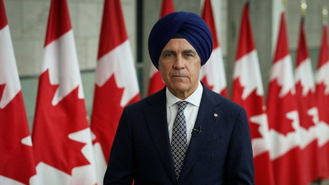 Canada Prime Minister Mark carney wearing a turban in front of Canada flags.